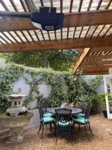un patio con mesa y sillas bajo una pérgola de madera en Gorgeous, private cottage in prestigious Newlands. en Ciudad del Cabo