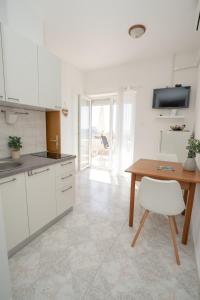 a kitchen with white cabinets and a wooden table at Apartments and rooms LJUBICA in Lun