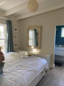 1 dormitorio con 1 cama blanca grande y espejo en Gorgeous, private cottage in prestigious Newlands., en Ciudad del Cabo