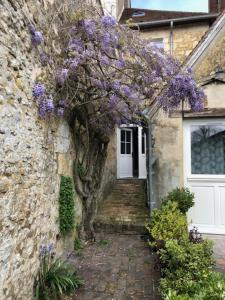 a house with purple flowers on the side of it at NATIFRIENDLY-Appartement centre historique avec jardin IDEAL FAMILLE in Bellême