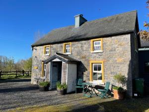 een klein stenen huis met een tafel en stoelen bij Mai's Cottage Suite - Charming Holiday Rental in Kilmallock