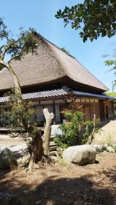 un bâtiment avec un arbre devant lui dans l'établissement 能登ごはん農場 暮らしの宿じろざみ, à Nanao