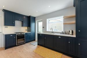 a kitchen with blue cabinets and a sink and a window at Quiet Cotswold Bungalow in Charlbury