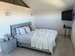 um quarto com uma cama com lençóis brancos e uma televisão em Immanuel Villa em Ptghni
