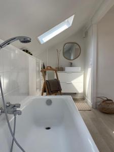 een witte badkamer met een bad en een spiegel bij Le nid des mésanges in Buffon