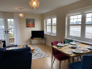 een woonkamer met een tafel en stoelen en een televisie bij Harbourside in Garlieston