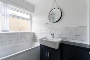 a white bathroom with a sink and a mirror at Quiet Cotswold Bungalow in Charlbury +5 photos