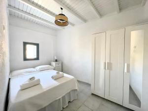 a white bedroom with a white bed and a ceiling at Black Pebble Myconian House in Ano Mera