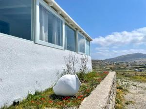 a building with a large white rock sitting next to a wall at Black Pebble Myconian House in Ano Mera