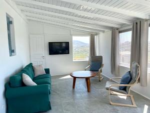 a living room with a couch and chairs and a table at Black Pebble Myconian House in Ano Mera