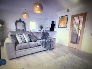 a living room with a couch and a kitchen at Luxurious 3 bedroom house Shangri la in village of Alfrick with free off road parking for 3 cars in an area of outstanding natural beauty, superb walking,close to Worcester, Malvern showground, theatre, Malvern hills, dogs welcome in Worcester
