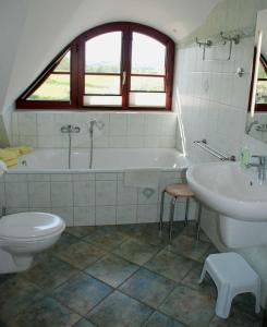 a bathroom with a tub and a toilet and a sink at Ferienhaus unterm Reetdach in Ostseebad Sellin