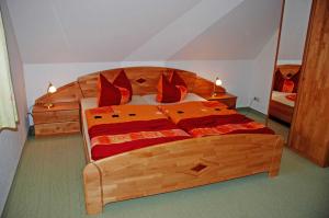 a bedroom with a large wooden bed with red pillows at Ferienhaus unterm Reetdach in Ostseebad Sellin