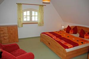a bedroom with a large bed and a red chair at Ferienhaus unterm Reetdach in Ostseebad Sellin
