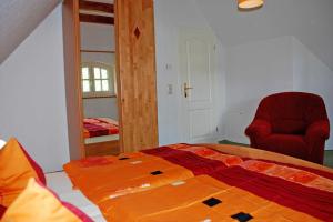 a bedroom with a bed and a red chair at Ferienhaus unterm Reetdach in Ostseebad Sellin