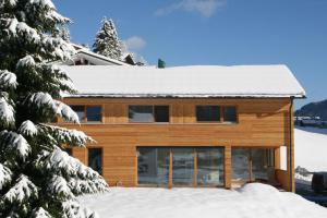 une maison en bois avec de la neige sur le toit dans l'établissement hus9, à Mittelberg