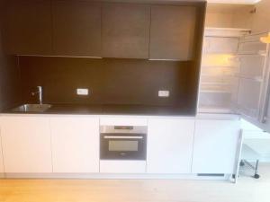 cocina con armarios blancos, fregadero y nevera abierta en Appartement au Centre Ville, en Bruselas
