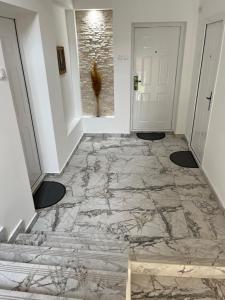 a hallway with a marble floor and white walls at Apartmani Tesla in Soko Banja
