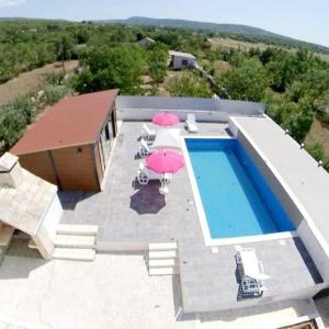 einen Blick über einen Pool mit Sonnenschirmen in der Unterkunft Villa RoseMary near Split in Donje Ogorje