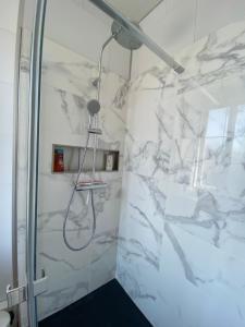 y baño con ducha y paredes de mármol blanco. en Grey Cosy, en Louviers