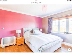 a bedroom with pink walls and a bed and a window at King's Suite at The Copthorne, Colwyn Bay, LL29 7YP in Colwyn Bay