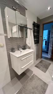La salle de bains blanche est pourvue d'un lavabo et d'un miroir. dans l'établissement Apartament Presto 17 by Housine, à Zator