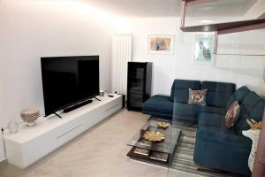 ein Wohnzimmer mit einem blauen Sofa und einem Flachbild-TV in der Unterkunft Vampolieri luxury home in Aci Catena