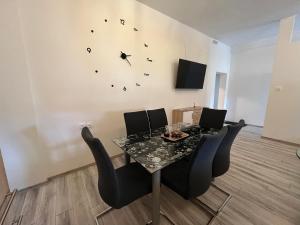 uma sala de jantar com uma mesa e um relógio na parede em Apartment Tilia em Otočac
