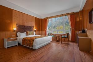 una camera d'albergo con letto e finestra di Summit Gangchen Hotel a Lachen
