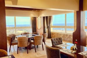 Un comedor con mesa y sillas y ventanas. en Grand Hotel Port Said, en Puerto Saíd