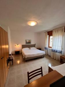 Hotel La Capannina في أريتزو: غرفة نوم بسرير وطاولة وكراسي