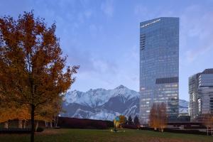 ein hohes Gebäude in einer Stadt mit einem Berg in der Unterkunft The Ritz-Carlton, Almaty in Almaty