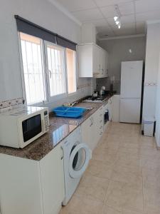 eine Küche mit weißen Schränken, einer Mikrowelle und einem Kühlschrank in der Unterkunft Villa Noemi, con piscina privada in Calpe