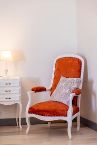 una silla naranja y blanca sentada junto a una cómoda blanca en MONTISMAURELLI, en Montmoreau