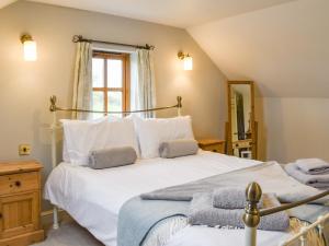 a bedroom with a large white bed and a window at The Tallet Barn in Marhamchurch