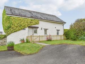 a white cottage with ivy on the side of it at The Tallet Barn in Marhamchurch