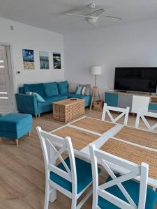 sala de estar con sofá azul, mesa y sillas en Dom nad morzem, basen, plaża, siłownia, plac zabaw, kort tenisowy, en Ustronie Morskie