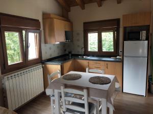 a kitchen with a table and a white refrigerator at Ribera del Sella II in Cangas de Onís +8 photos