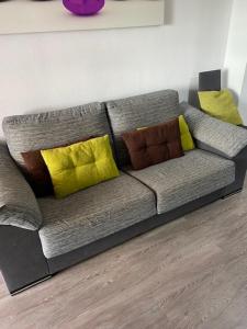 a gray couch with yellow pillows in a living room at Apartamento Costa Marina 3 in El Borseral