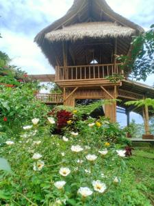 una casa en el árbol con techo de paja y flores en Lembah Cinta Mayungan, en Baturiti
