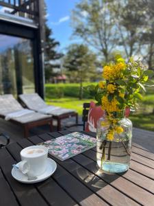 una mesa con un jarrón de flores y una taza de café en NaturApartments & Spa en Burg (Spreewald)