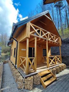 een grote houten hut met een veranda en een terras bij Pokoje i Domki Na Szlaku in Polanica-Zdrój
