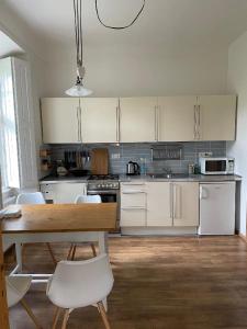 a kitchen with white cabinets and a wooden table and chairs at Apt. overlooking the castle Nižbor20km from Prague in Nižbor