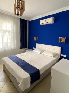 1 dormitorio con 1 cama grande y pared azul en pH Hotel, en Ölüdeniz