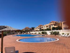 einen Pool mit Stühlen und Sonnenschirmen in einem Resort in der Unterkunft Las Rocas Golf and Sea in Caleta de Fuste
