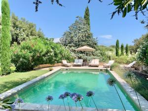 a swimming pool in a yard with chairs and flowers at La Bastide in Le Plan-de-la-Tour