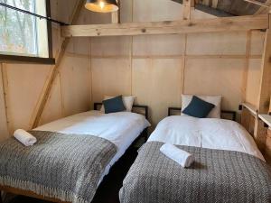 two twin beds in a small room with a window at The Shack in Hakuba