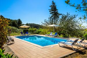 a swimming pool with chairs and umbrellas in a yard at Villa Can Pep D'en Puig in Sant Mateu d’Albarca