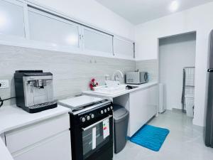 a kitchen with white cabinets and a black appliance at New! Your home in Israel Luxury Suite in Bat Yam