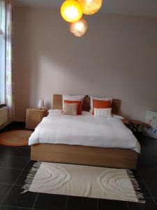 Un dormitorio con una cama con sábanas blancas y almohadas naranjas. en 'Nulle Part Ailleurs', en Dinant